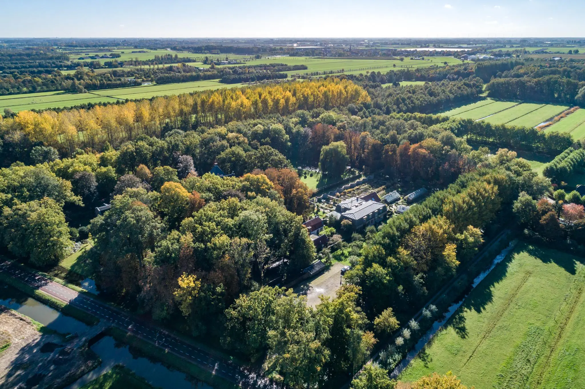 Luchtfoto van het groenrijke landschap rond de Langbroekerdijk A met boerderijen en omliggende weilanden.